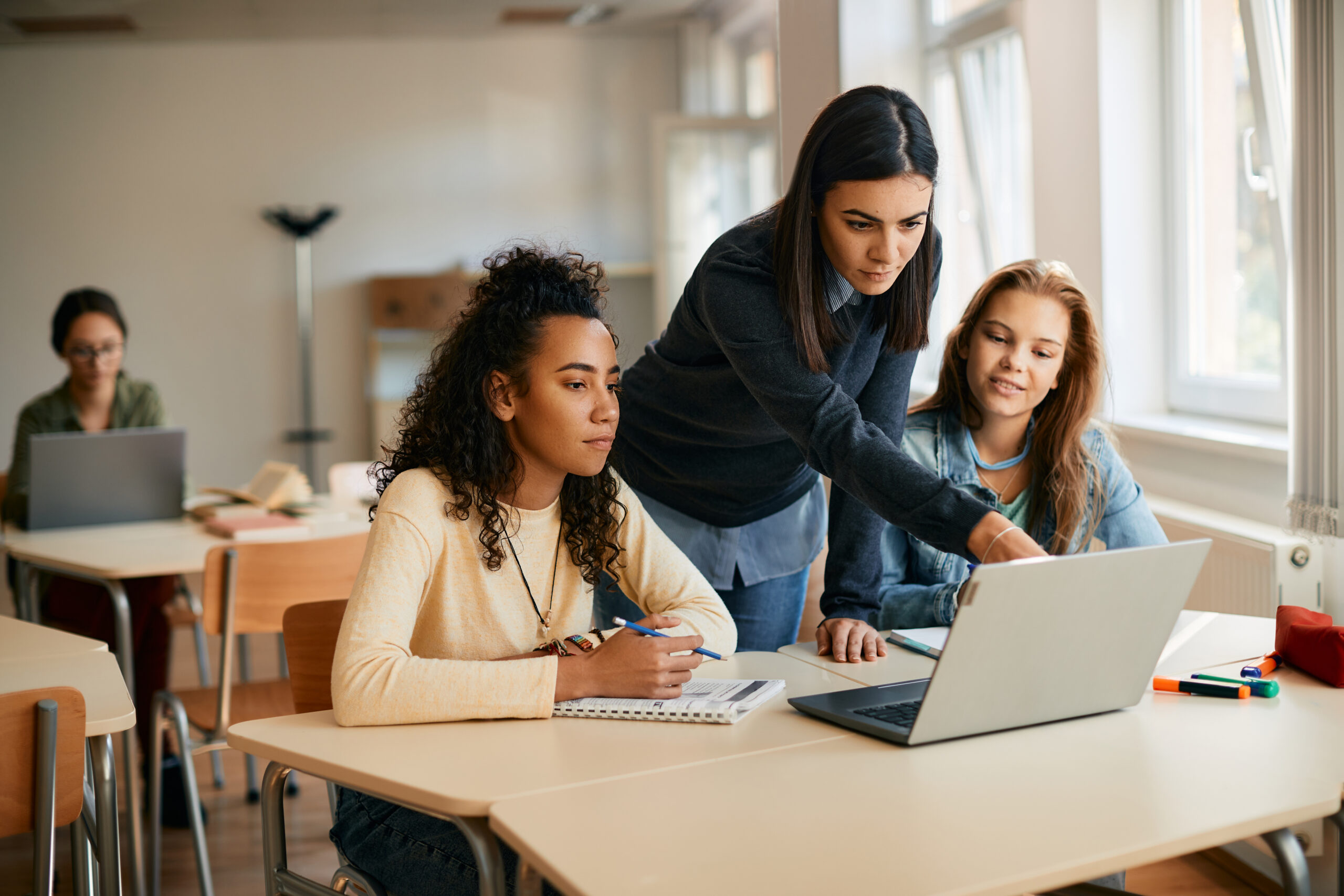 Women volunteer with black and white high school students