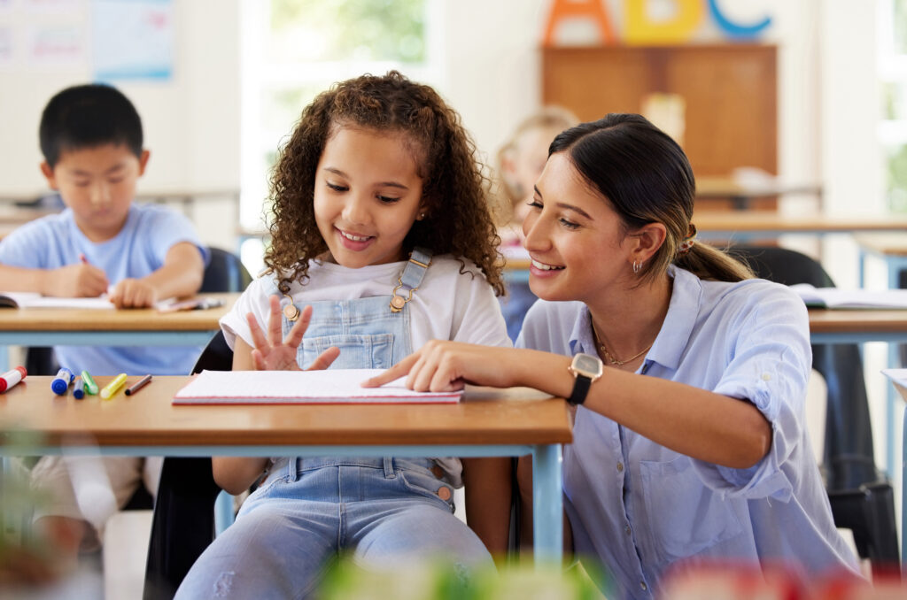 female teacher assisting a preschool learner in her class